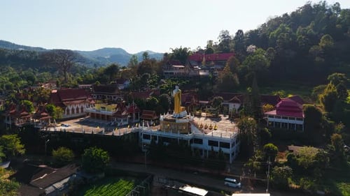 Golden Buddha Statue Positioned Within Wat Pong Yaeng Nok Temple Surrounded By Verdant Mountain