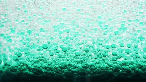 macro shot of dark blue bubbles setting on ground of water with a bright yellow background