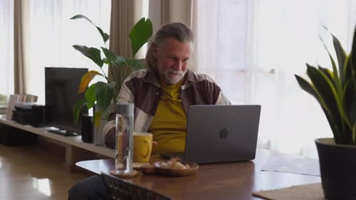 Man Using Laptop, Smiling and Waving at the Camera