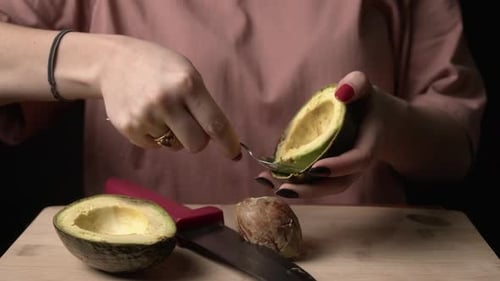 Woman Scooping Avocado Flesh – Close-Up Food Preparation