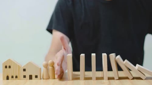 Nahaufnahme bei der Hand eines Mannes, der anhält, besteht die Gefahr, dass die Holzklötze auf ein paar Personen und nach Hause fallen