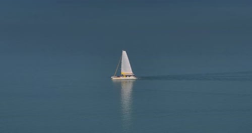 View From a Drone of a Yacht with White Sails Sailing Along the Blue Surface of the Sea in Good