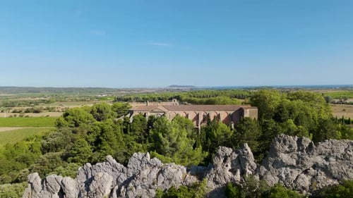 Aerial dolly shot of an abbey in the countryside of France with a rocky landscape