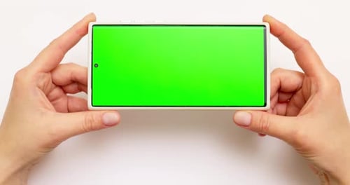 Woman's Hands Holding Smartphone with Green Screen on White Background