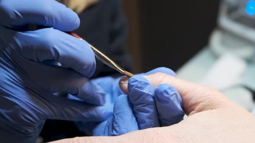 A middle-aged wealthy woman in a cosmetic spa receiving shiny gold glittering nail polish and manicu