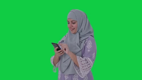 Happy Muslim woman using phone Green screen