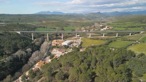 Aerial view of the bridge of the AVE train passing through a medieval village in the middle of the m