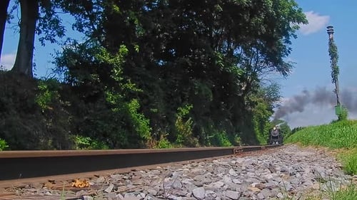 A Low Angle of a Steam Passenger Train Rumbling By Blowing Smoke on a Sunny summer Day