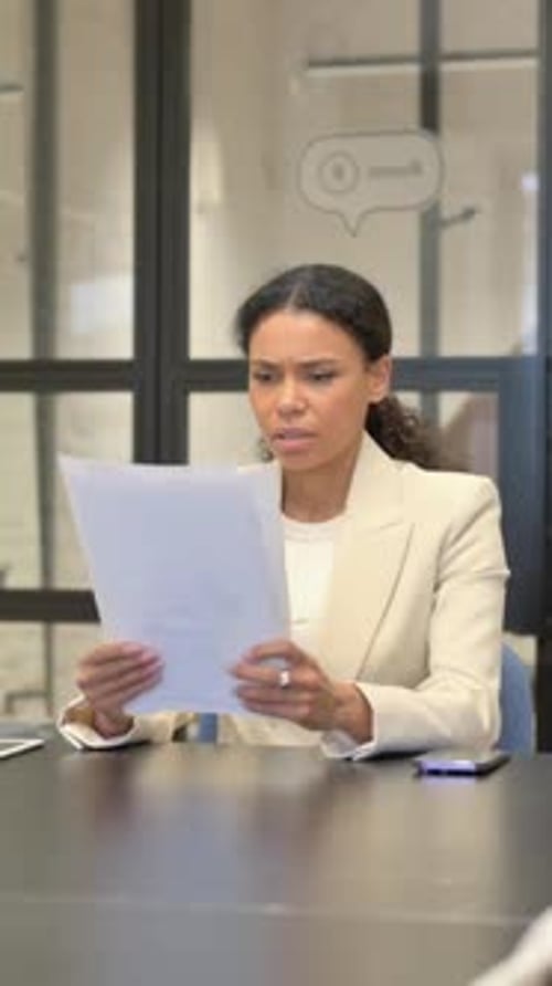 Frustrated Woman Reviews Documents in Modern Office