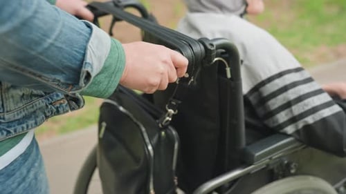 Adult Pushing Child in Wheelchair on Sidewalk