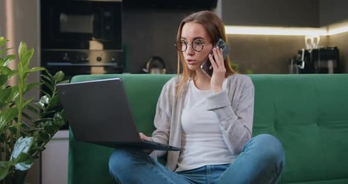Woman Working with Laptop and Talking on Phone