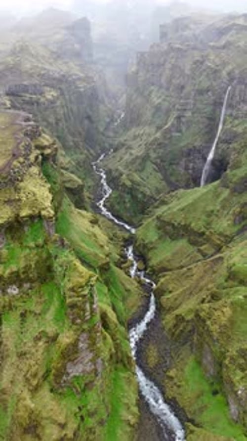 Aerial view of waterfall flowing through canyon, Iceland.