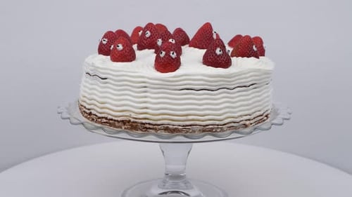 Iced Cake with Strawberries on Rotating Glass Stand