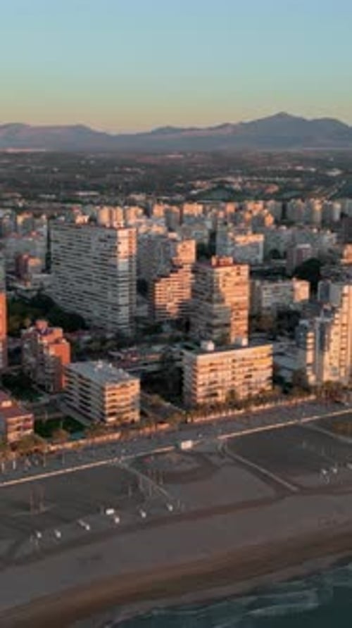 Aerial view of the beach and the buildings along the coastline in Alicante, Spain at sunset. Vertica