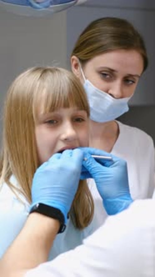 Little Girl Getting Teeth Checked By Dentist Hand in Mouth