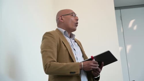 Professional Man Explaining Business Strategy Holding Tablet Indoors