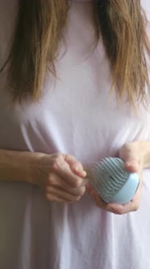 Woman Cleans Hairbrush with Blue Hair Cleaning Tool