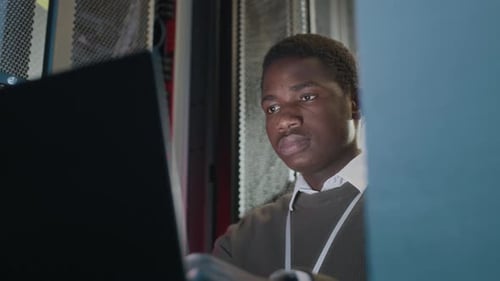 Young Adult Works on Computer in Server Room