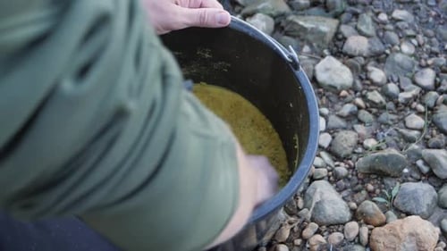 Mixing Yellow Material in Bucket Outdoors with Hands