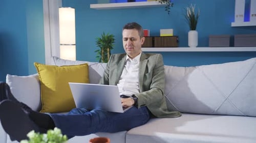 Man Relaxing on Sofa Using Laptop at Home