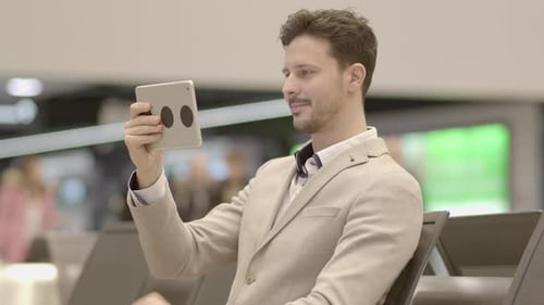 Portrait of Young Successful Man Using Tablet Screen on Business Travel Trip