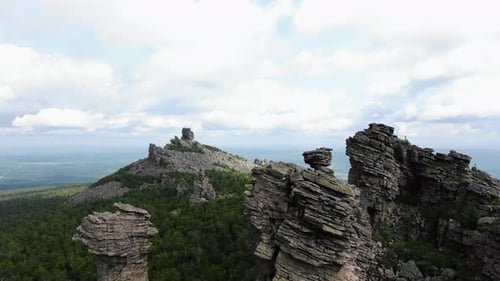 Aerial Shot Capturing the Dramatic Terrain of Rugged Mountain Peaks with Lush Forests Under a Cloudy