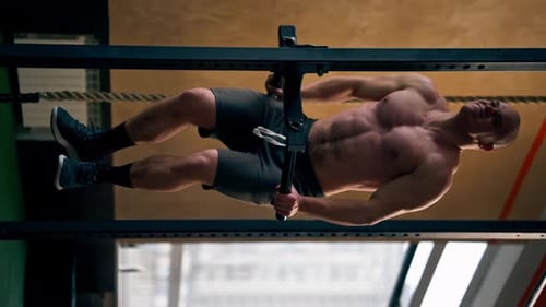 Vertical Video Close Up in the Gym Bald Trainer Does Pushups on the Horizontal Bar for Pushups and