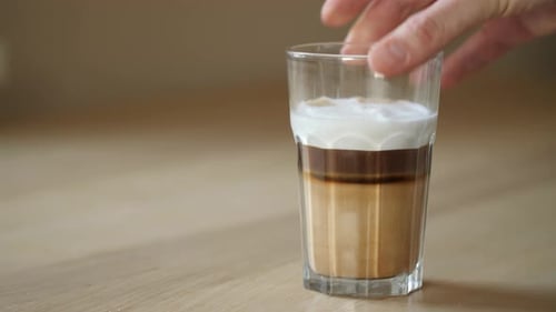 Hand Sets a Glass of Coffee on Table