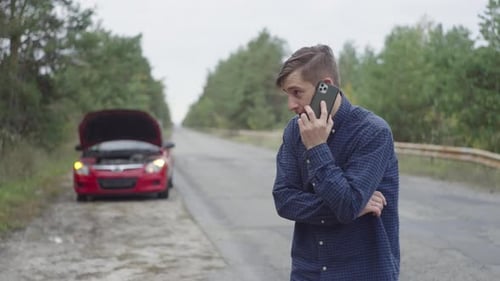 Man Talking on Phone Next to Broken Car