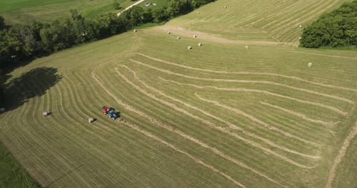 Luftaufnahme einer Traktorballenpresse, die nach der Weizenernte im Sommer über Feldern arbeitet.