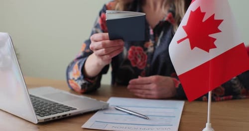Passport and Canadian Flag on Desk with Visa Application