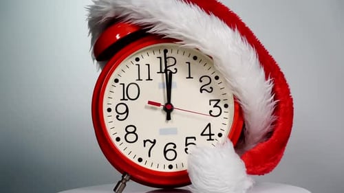 C'est un bonnet de Père Noël sur un réveil réglé pour se réveiller