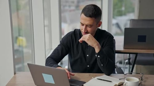 Jovem olhando para o laptop com cara de preocupação. O funcionário do sexo masculino está intrigado com alguns problemas de trabalho.