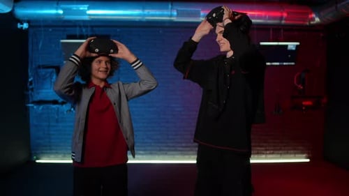 Two Teenagers Raise Their VR Glasses and Make a Gimme Five Gesture Looking at Each Other and