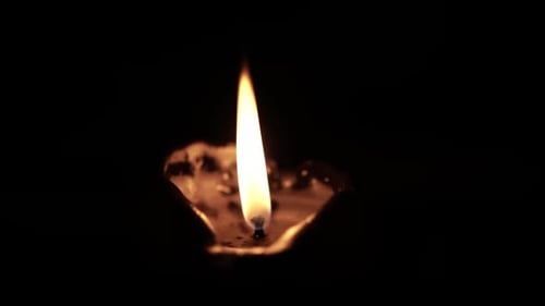 Glowing Candle Flame against Dark Background