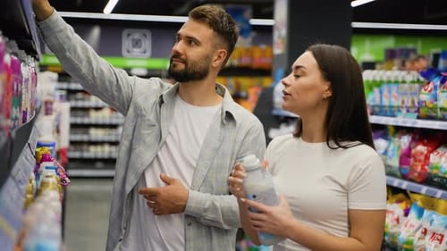 Jovem casal escolhendo amaciante de roupas no supermercado