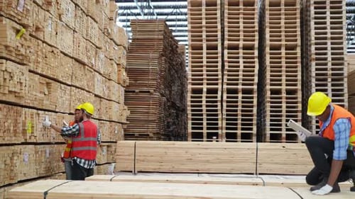Arbeiterin mit Uniform arbeitet an einer Holzschneidemaschine in einem Möbelhersteller.
