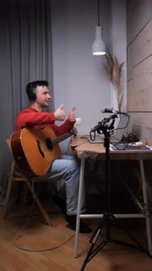 Man Playing Guitar and Video Conferencing at Home