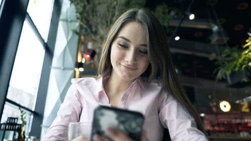 Young, Pretty Woman Using Smartphone Sitting in Cafe 20s