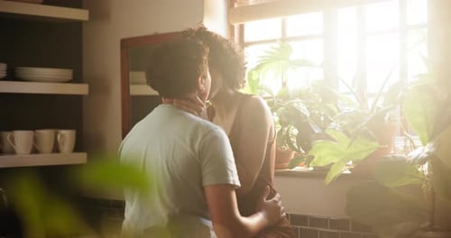 Affectionate Couple Embracing in Kitchen with Sunlight