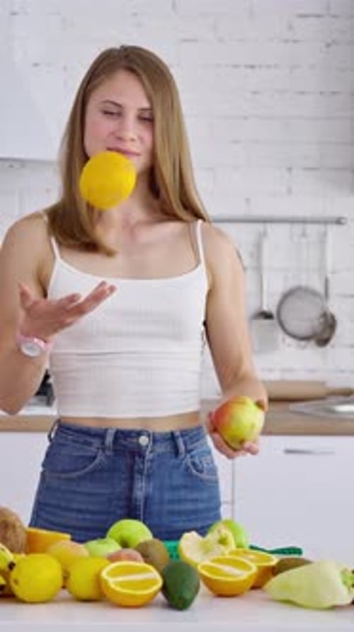 Portrait of beautiful girl in the kitchen. Vegetarian woman holding organic fruit.