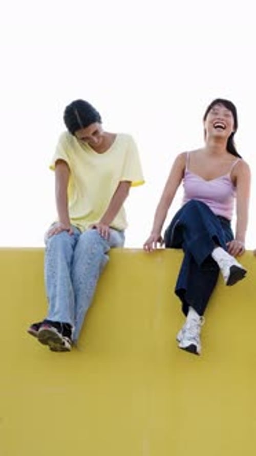 Two Cheerful Young Women Laughing Together on White Background Vertical