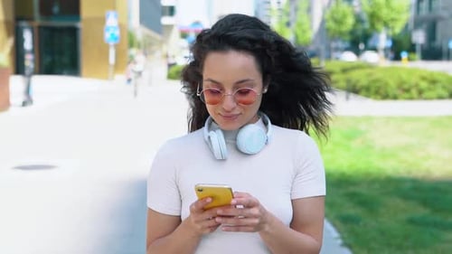 Smiling Young Woman Writing Message on Smartphone While Communicating Online Outdoor