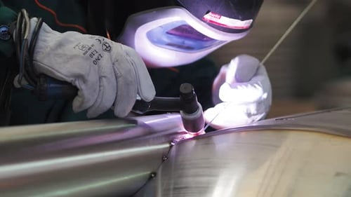 Welder, using VIG, TIG, MIG MAG method to welding stainless steel parts, close up. The welder uses a