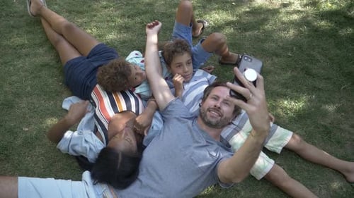 Family Lying on Grass Taking Selfie Together Outdoors