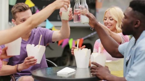 Friends Toasting Bottles at Urban Food Truck Gathering