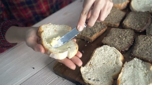 Butter being spread onto bread on wooden board