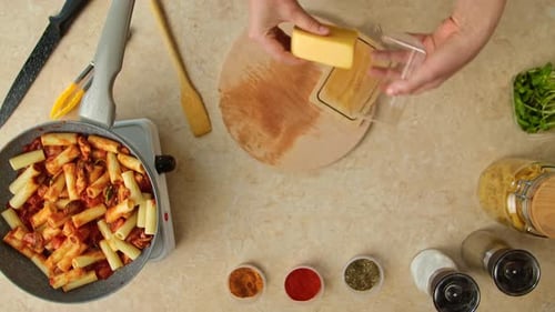 Overhead view of woman preparing pasta and cheese