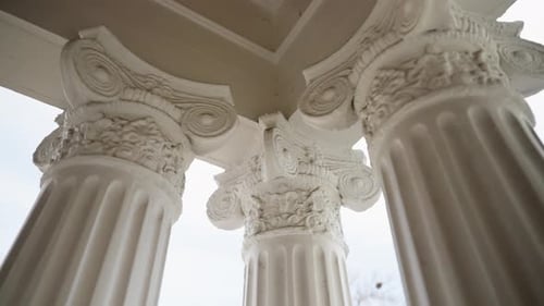 Upward view of ornate white Ionic columns with detailed capitals supporting a covered entry