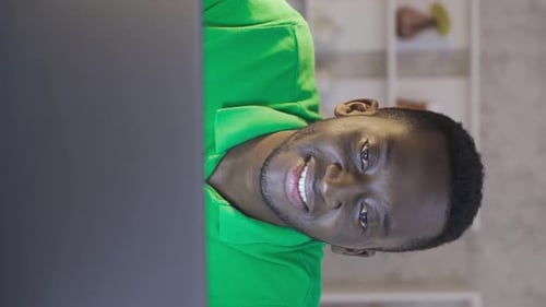 Vertical Video of Happy black businessman using laptop in home office, completing work.